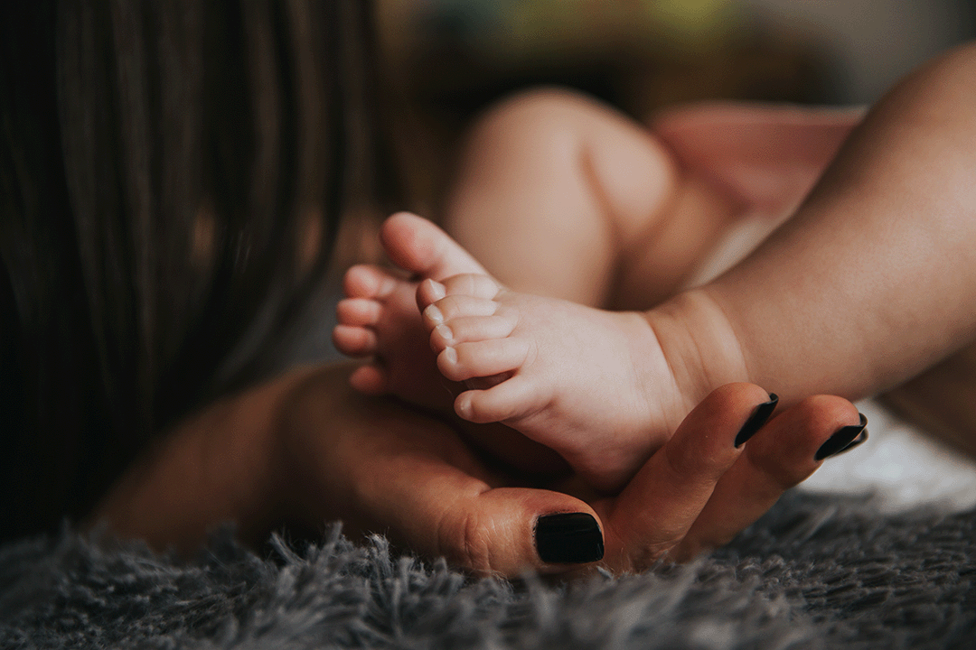 Holistic sleep specialist infant feet being held by woman's hands