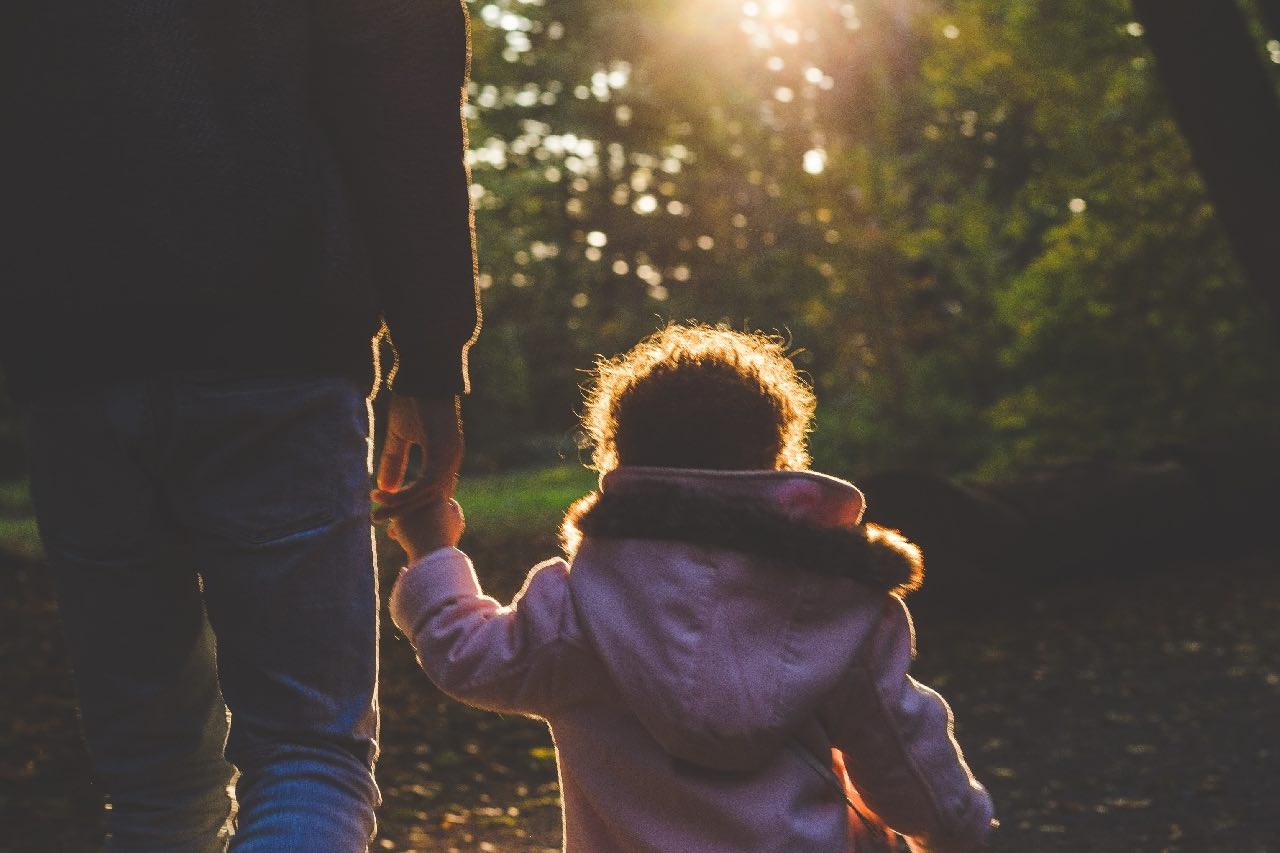 child-and-caretaker-walking-towards-sunshine